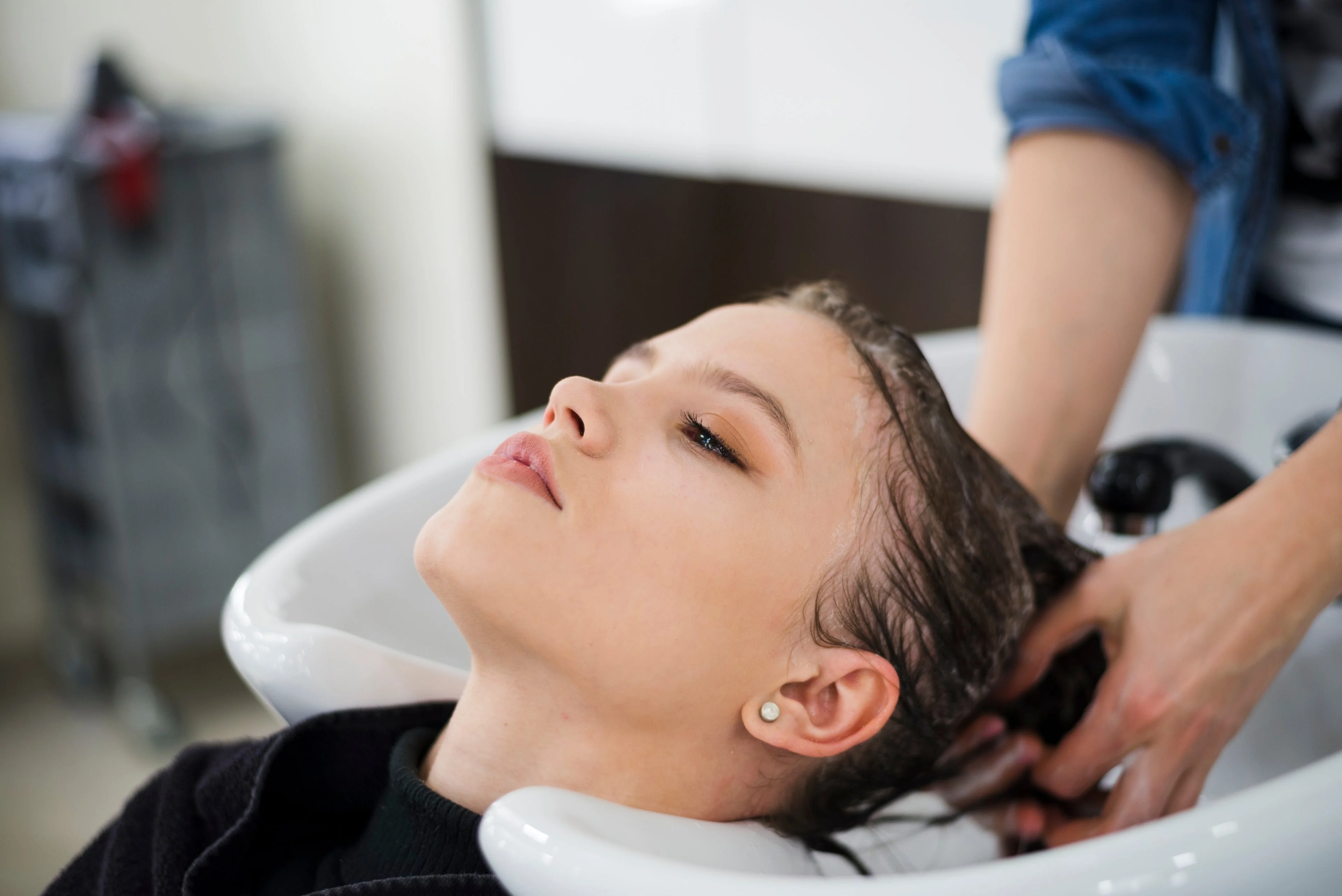 Brunette client at the basin, post-shampoo, ready to style